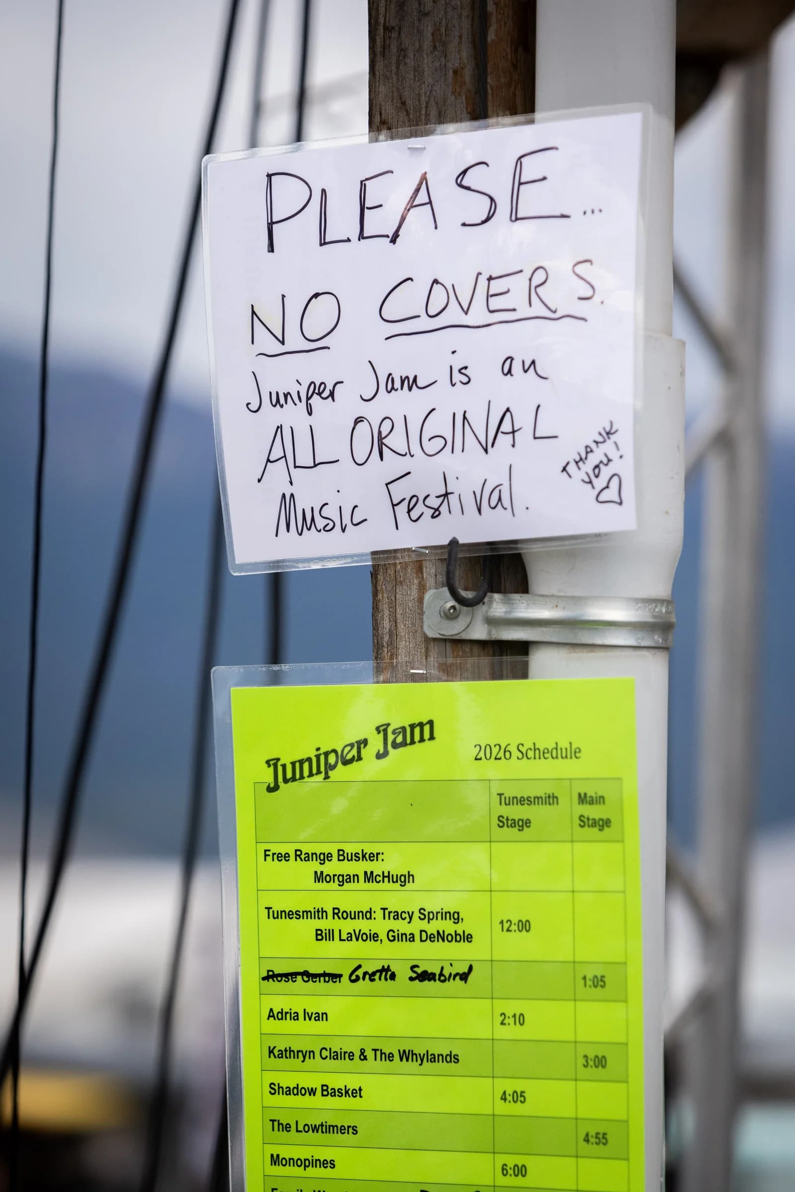 A hand-lettered reminder on a post beside the day’s schedule: no covers, Juniper Jam is an all-original music festival. Wallowa County Fairgrounds, September 5, 2026.